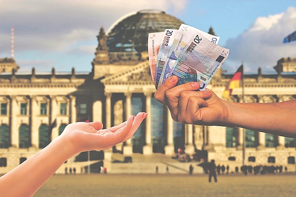 Männliche Hand gibt weiblicher Hand Euroscheine (ca. 100 €) vor dem Reichstagsgebäude