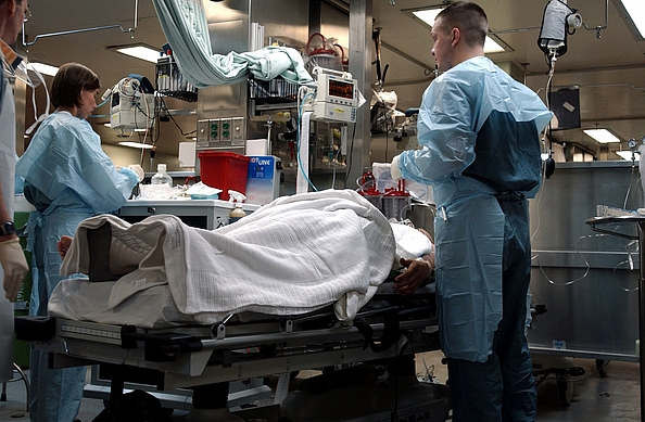 Symbolbild zeigt Krankenhauspersonal und Patienten unter Decke auf einem OP-Tisch