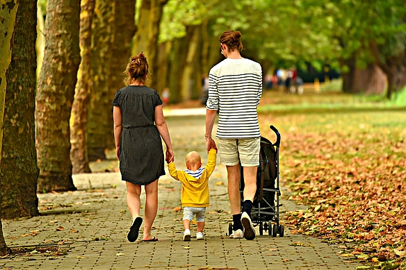 Kleinkind läuft Kinderwagen und Eltern